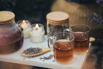 Natural herbal lavender tea on a white wooden tray in a middle of beautiful purple lavender field.