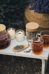 Natural herbal lavender tea on a white wooden tray in a middle of beautiful purple lavender field.