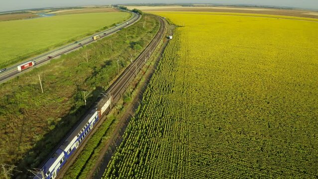 Romania infrastructure industry. Aerial 4k video with a passengers train travelling from Constanta to Bucharest next to A2 highway road.
