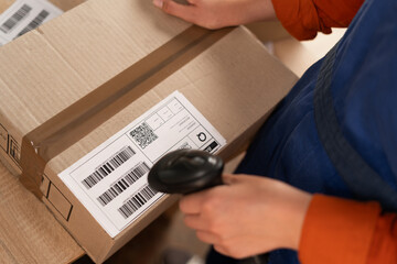 Female hands scanning barcode on delivery parcel. Worker in factory warehouse scanning labels on...