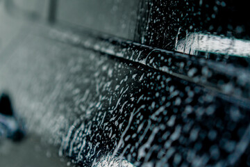 a close-up of the windshield and interior of a luxury car at the moment of a car wash using foam...