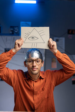 Strange man in a foil hat with masonic symbol All-seeing eye of God. Fake news conspiracy theories