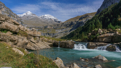 small waterfall in Ordesa valley in pyrenees mountains with snow caped Monte Perdido, Ordesa and Monte Perdido National Park, Huesca, Aragon, Spain