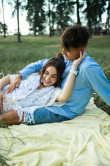 Happy pregnant couple sitting on the grass in park. Happy and young pregnant couple hugging in nature.