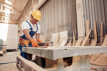 Male builder using industrial woodworking equipment in workshop