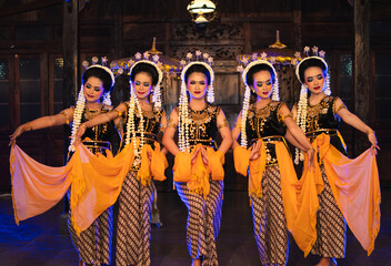 a group of Javanese dancers holding yellow shawls while dancing on stage