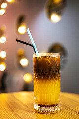 Iced coffee in a glass with straw on a wooden table.