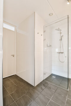 a white bathroom with black tile flooring and gray tiles on the walls there is a walk in shower stall