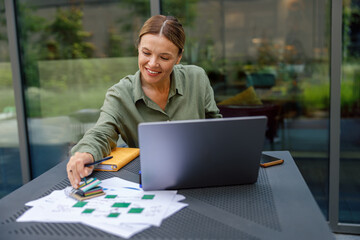 Woman manager working with documents and use laptop sitting on cafe terrace