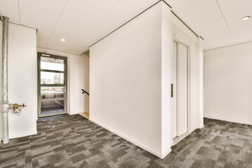 an empty office space with white walls and grey carpeting, there is a door leading to the left side