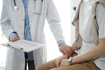 Doctor and patient in clinic. Friendly physician examining a young woman with a one hand while...