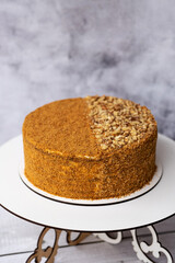 Homemade honey cake with sour cream on a wooden table with nuts.