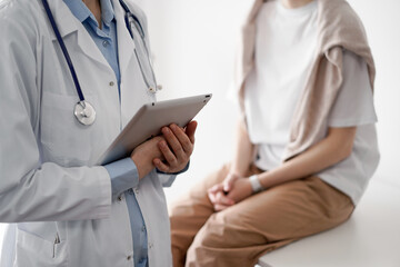 Doctor and patient discussing perfect health exam results. Friendly physician keeping tablet computer with her hands near a young woman. Medicine concept