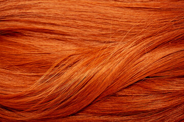 Red hair close-up as a background. Women's long orange hair. Beautifully styled wavy shiny curls....