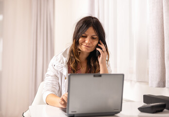 Portrait of smiling woman talking on phone and laptop in front