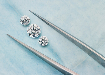 3 Round Diamonds. 3 Stone Diamond Photograph on Blue Background with Diamond Tweezers. Graduated...