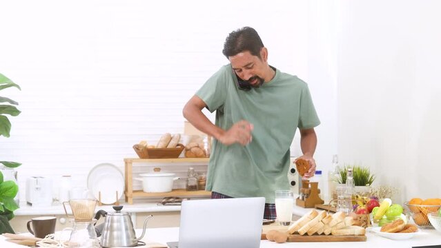 Middle-aged Man Hungry Walks To Kitchen Hurry To Take Some Food And Milk While Talking With Colleagues To Check Work, Lifestyles Asian Man In Casual Wake Up Early Morning  Start Working At Home