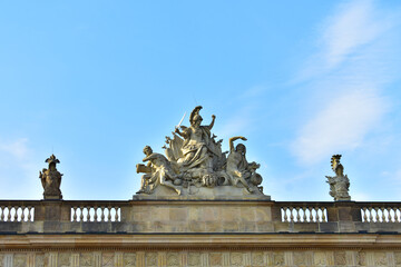 Ancient sculptural group of male warrior with sword, two men and military attributes on the roof of the building. Germany, Berlin, August 2022.