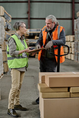 Vertical image of manager talking to worker during their work in warehouse