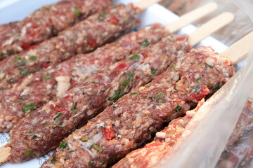 Raw Adana kebab on a plate, ready for grill