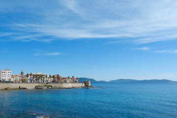 Panorama of coast of Alghero in spring Sardinia, Italy. Alghero cityscape seen from far under vibrant clear blue sky