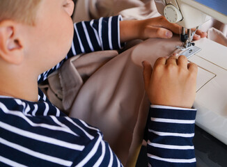 Teenager, boy learns to sew on a sewing machine at home, hands close-up. Concept - hobbies -...