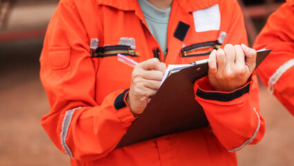 Action of a supervisor is writing on paper which in clipped on clipboard for taking report during...