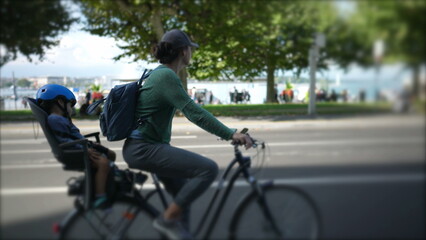 Mother riding bicycle in urban street with child in back seat sleeping