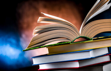 A composition with an open book lying on a stack of other books