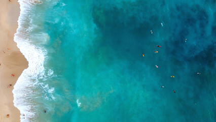 Top view of surfers in the ocean next to Bali beach. Surfing in the Indian Ocean