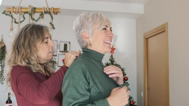 Woman Putting A Necklace On Her Wife While They Celebrate Christmas Together.