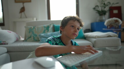 Young boy using computer keyboard and mouse in front of screen