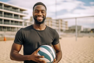 Portrait of a smiling african american man holding a volleyball on the beach