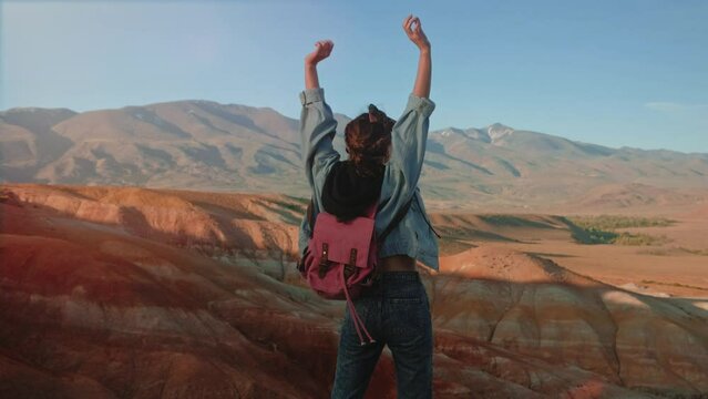 Hiker woman standing with hands up achieving the top. Girl welcomes a sun. Successful woman hiker open arms on sunrise mountain top. Freedom, sport, success and mental health concept