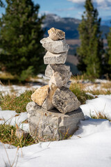 Stone man cairn in snow between green fir trees