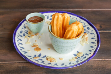 Churros avec une sauce chocolat dans une assiette en céramique. Spécialité culinaire espagnole...