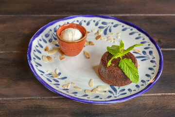 Mi-cuit au chocolat avec une boule de glace à la vanille et une feuille de menthe dans une assiette en céramique. 