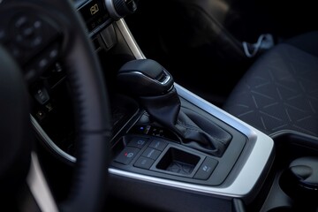 A portrait of an automatic gear shift stick in a hybrid car, meaning it drives on fossil fuel and...