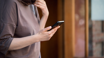 Female hands with mobile, woman outdoor at city street, close up, selected focus.