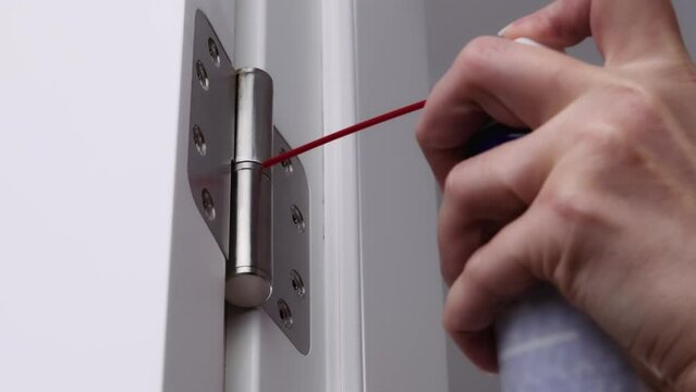 A man is oiling the door hinges. adjusting door hinge using lubricating oil.