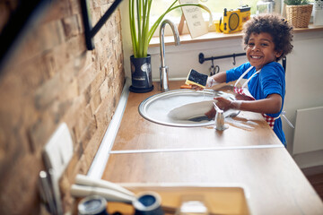 Bubbles and Smiles: Afro-American Boy Embraces Sudsy Dishwashing Fun