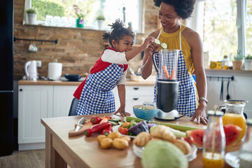 Afro-American Mother and Daughter Transforming Vegetables into Healthy Blends