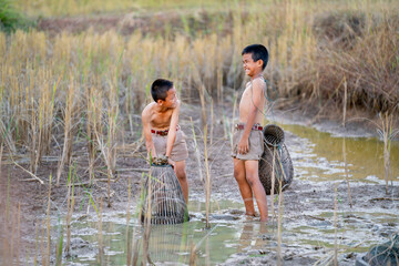 Two Asian little boys look fun with fail to catch fish in rice field with mud and clay and they look happy and enjoy.