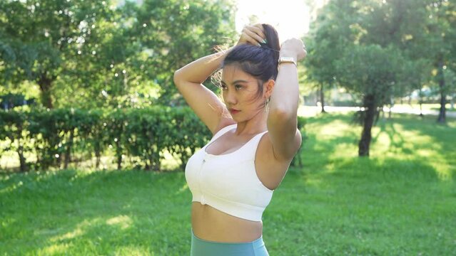 Young Asian female woman doing workout, stretching, jogging and running at a city park. Footage is part of a series of 23 different shots, including tying shoe laces, using sunglasses, resting, etc.