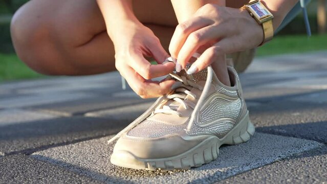 Tying shoes laces at the park, preparing to workout. Footage is part of a series of 23 different shots, including tying shoe laces, using sunglasses, resting, etc.