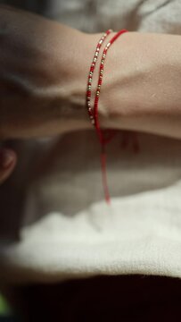 a bracelet made of red thread on the wrist of a woman's hand symbolizing a text in the form of Morse code. a broslet ornament on a woman's hand. close-up vertical video