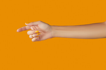 Womans hand with jewelry accessories over orange background