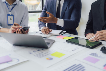 Business documents on office table with smart phone and calculator digital tablet and graph business with social network diagram and two colleagues discussing data working in office