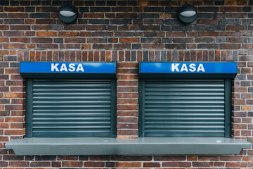 Two closed cashier windows against a background of brick wall   - 626022570