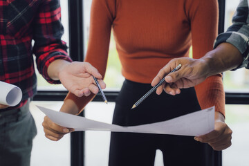 Engineer and contractor planning projects together at desk with blueprints.